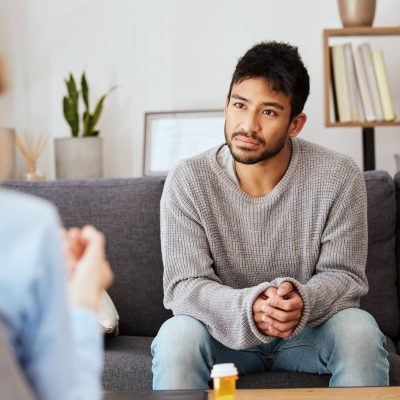 Shot of a young man having a therapeutic session with a psychologist.